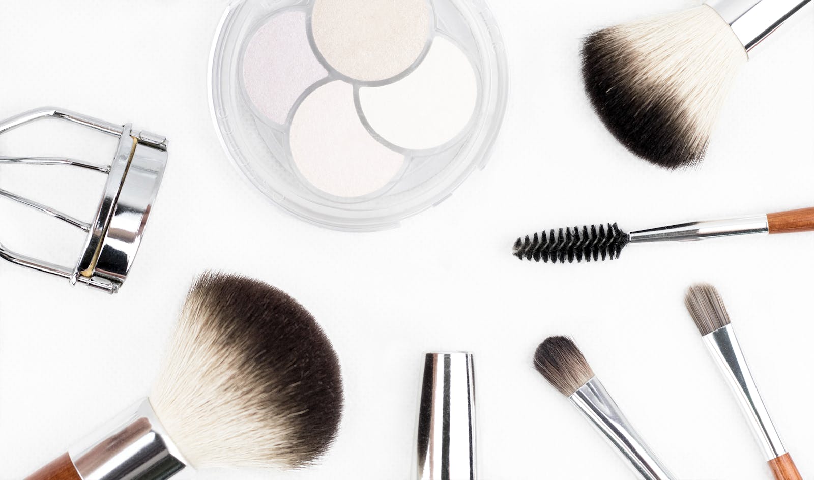 Flat lay of various makeup brushes and tools on a white background.